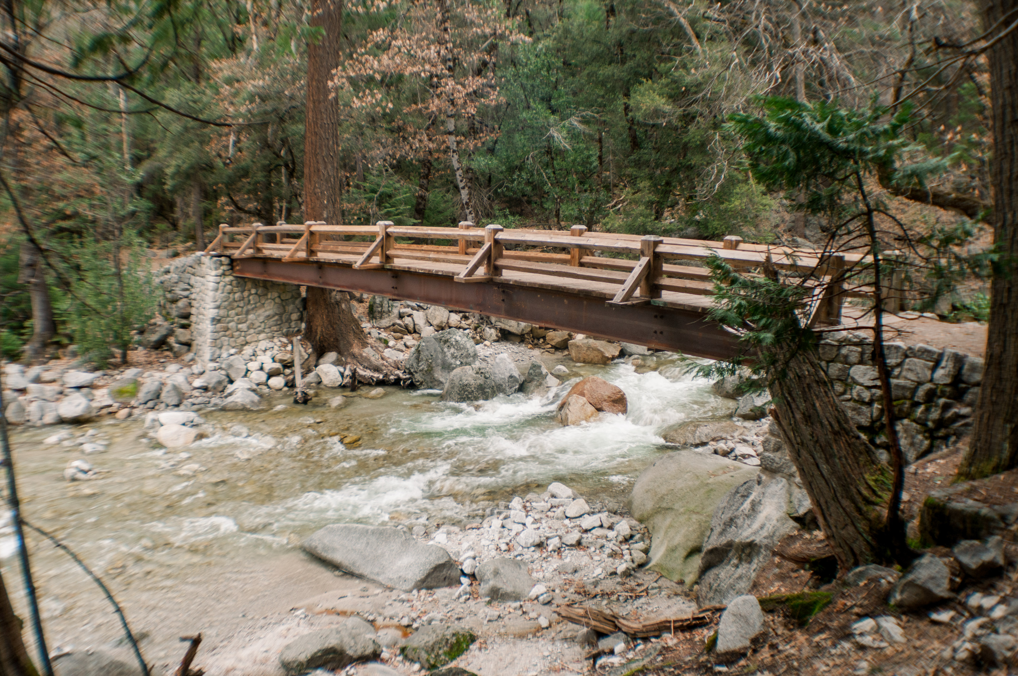 A Bridge near Mirror Lake in Yosemite National Park in California in the United States.  A bridge with slow flowing water underneath it.  The water is clear and running from higher up on the mountains.
